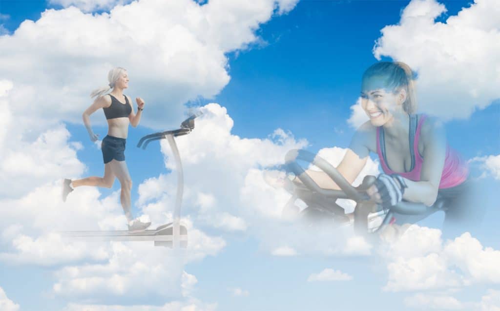 two women - 1 on treadmill 1 on a bike in the clouds smiling at each other