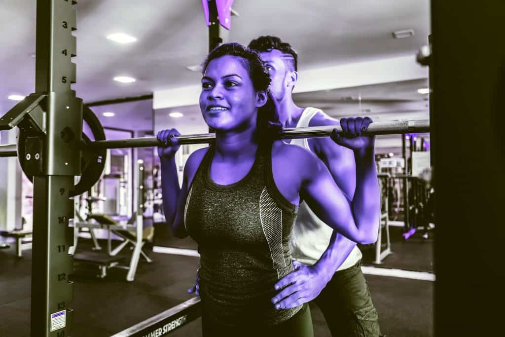Woman & partner doing squats on the Legs part of their Push Pull Legs training split - heydayDo image