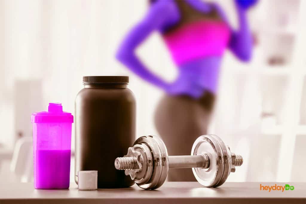 Woman in background drinking her pre workout supplement, from the article Pre Workout Side Effects on heydayDo